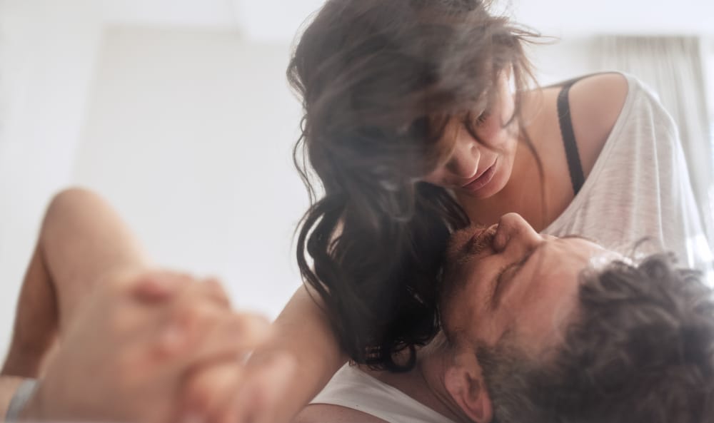 cute young couple embracing on white bed and having fun on weekend together - Leo Man and Scorpio Woman Love Compatibility