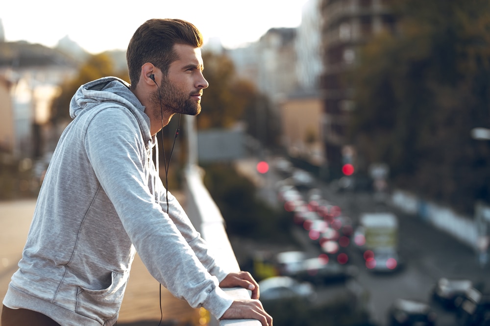 young man in headphones looking away while standing on the bridge - Leo Man with Virgo Cusp